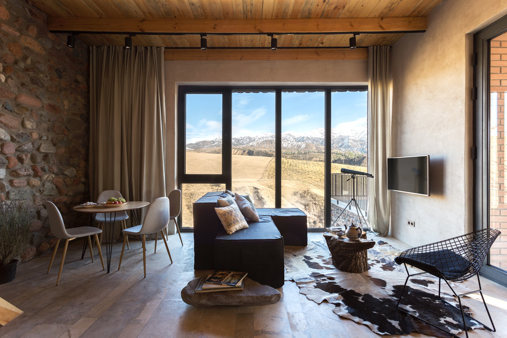 Diseño de salón abierto rural de tamaño medio sin chimenea con paredes marrones, suelo de travertino, televisor colgado en la pared, suelo beige y piedra