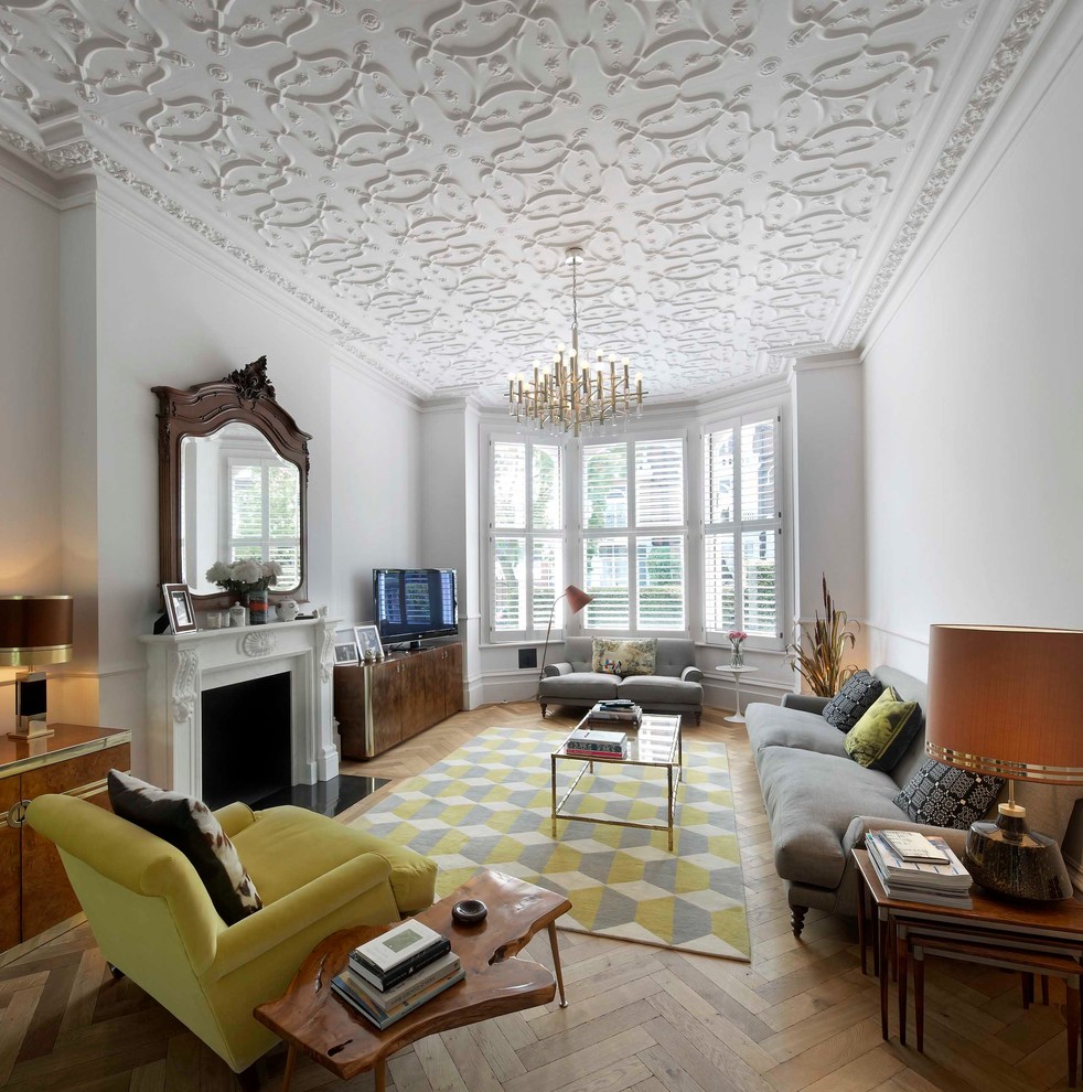 Aménagement d'un salon gris et jaune classique avec un mur blanc, un sol en bois brun, une cheminée standard et éclairage.