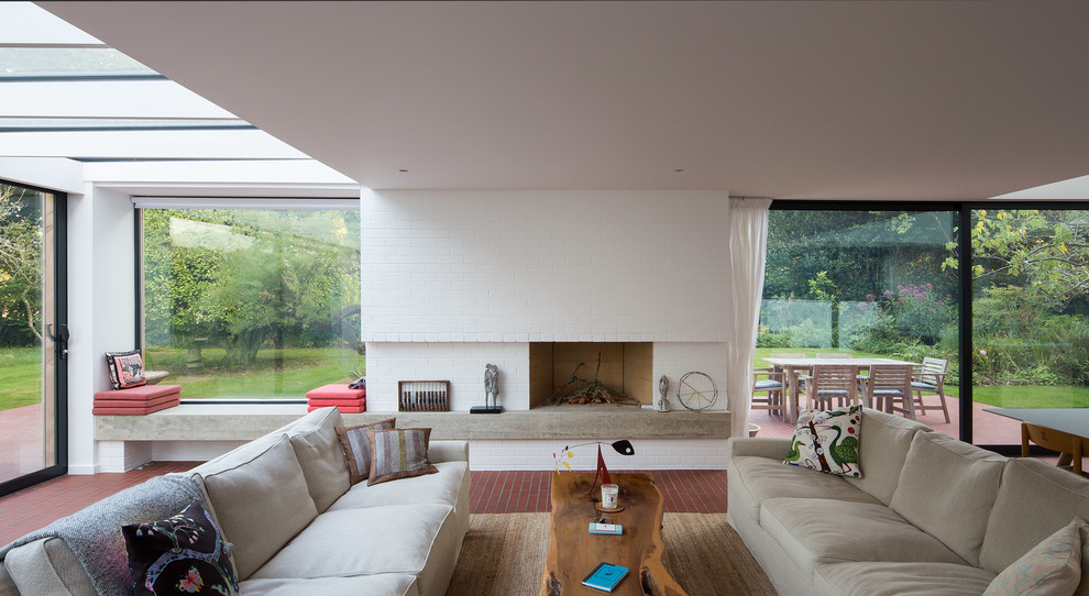 This is an example of a contemporary open plan living room in Hampshire with white walls, brick flooring, a standard fireplace and a brick fireplace surround.