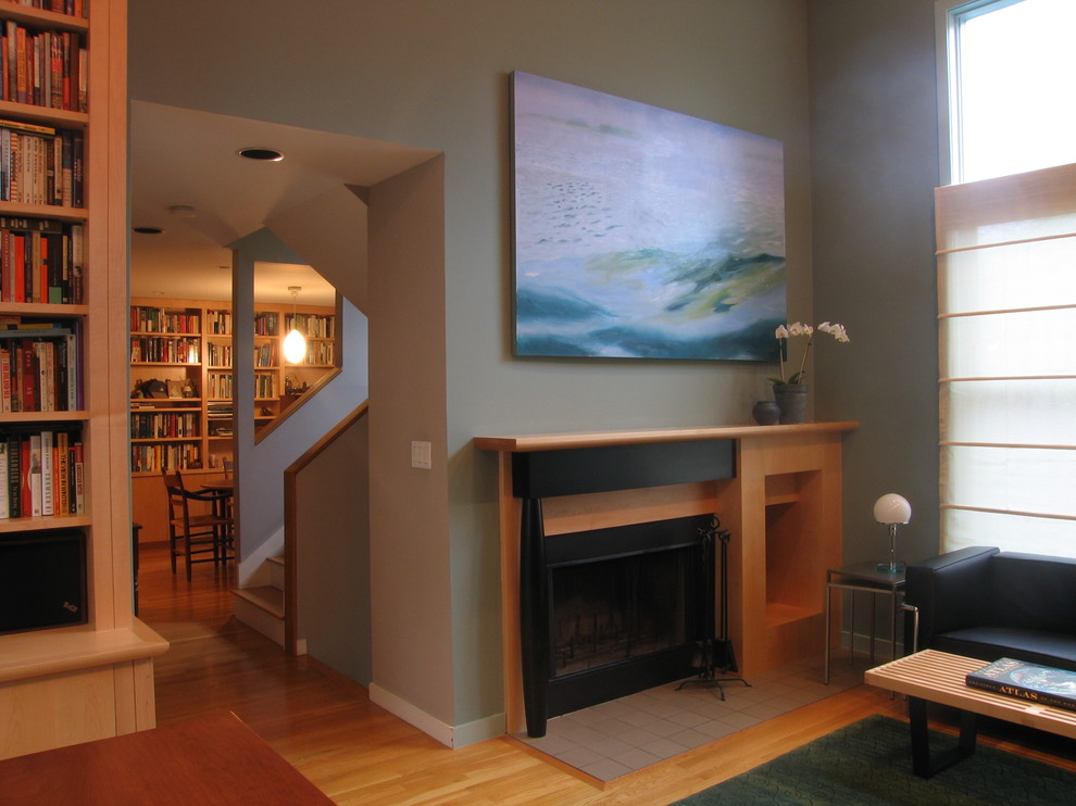 Cette photo montre un salon tendance de taille moyenne et ouvert avec un sol en bois brun, une cheminée standard, une bibliothèque ou un coin lecture, un mur vert et un manteau de cheminée en bois.