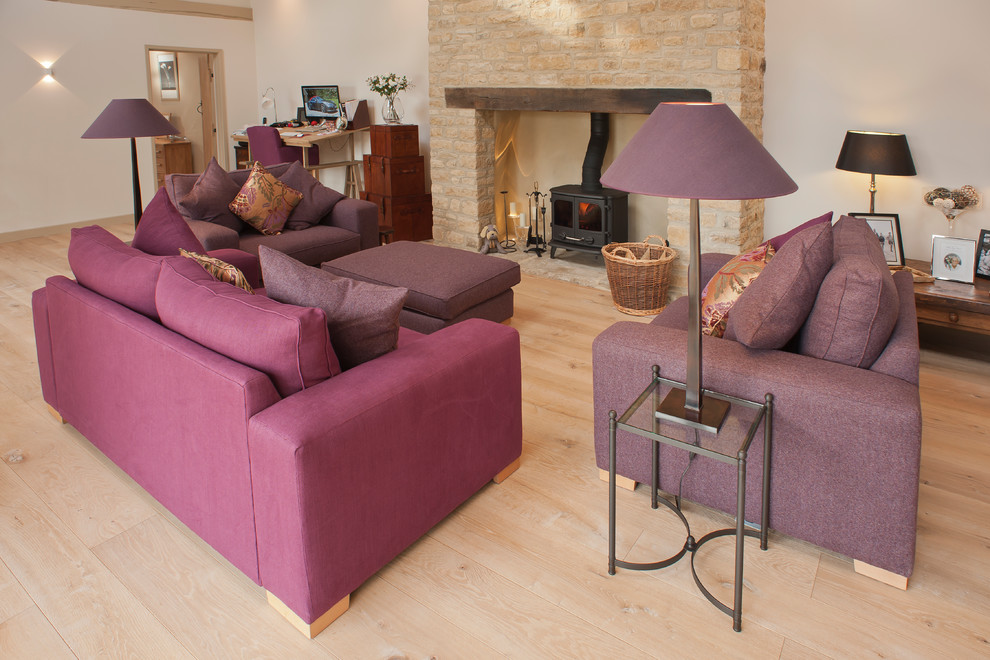Large rural enclosed living room in Oxfordshire with light hardwood flooring, a wood burning stove, a wooden fireplace surround and a wall mounted tv.