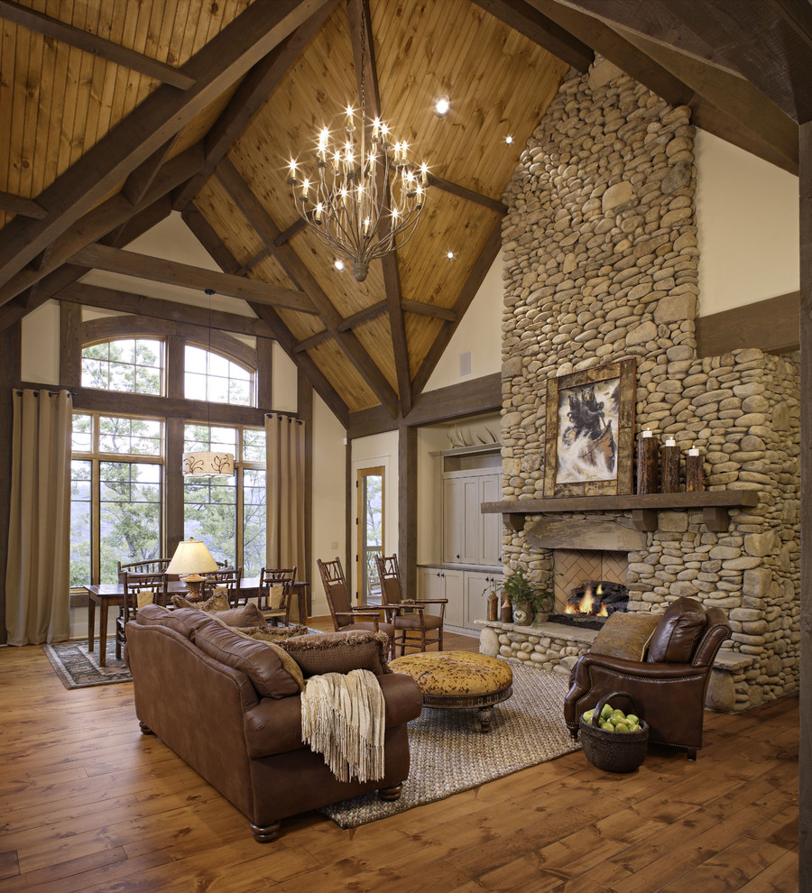 Idée de décoration pour un salon chalet ouvert avec une cheminée standard, un manteau de cheminée en pierre et éclairage.