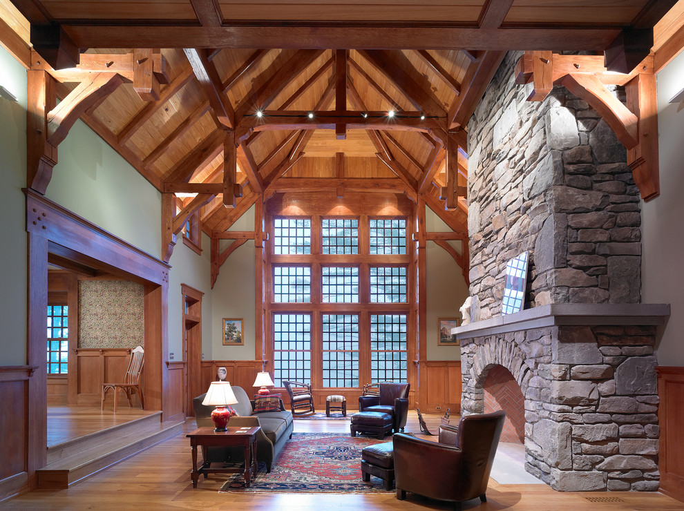 Cette photo montre un grand salon craftsman fermé avec une salle de réception, un mur vert, un sol en bois brun, une cheminée standard, un manteau de cheminée en pierre et aucun téléviseur.