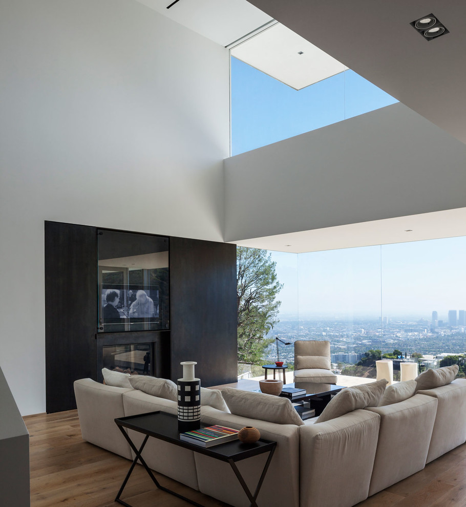 Immagine di un grande soggiorno contemporaneo aperto con parquet chiaro e parete attrezzata