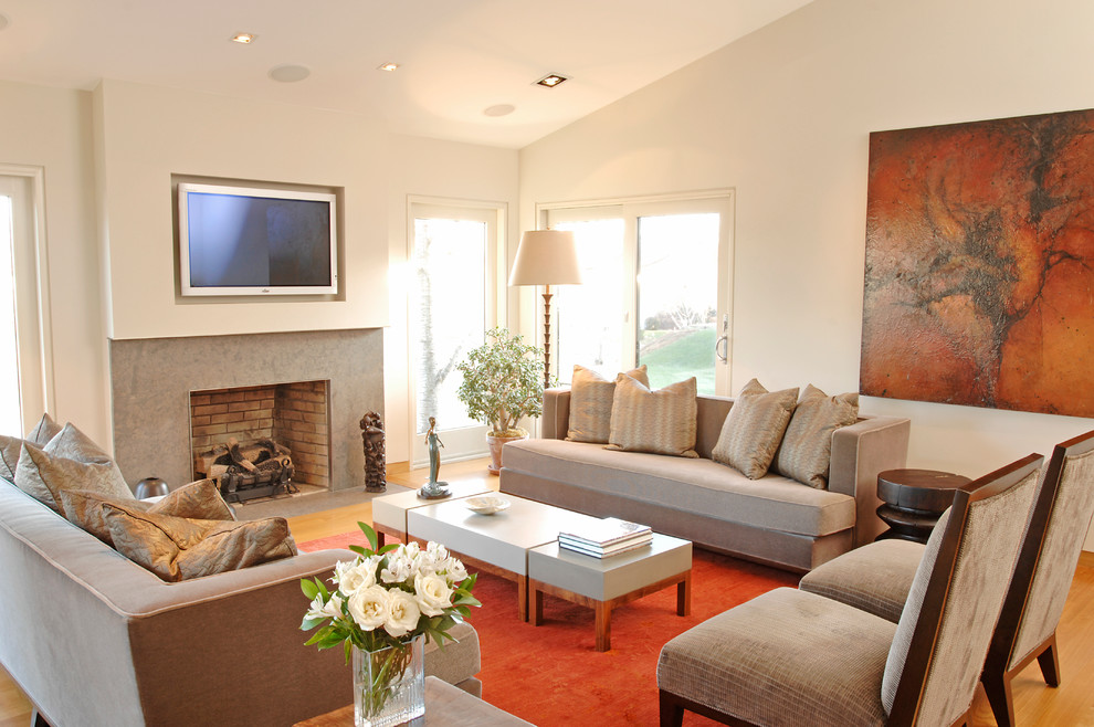 Foto de salón actual con paredes beige, suelo de madera en tonos medios, marco de chimenea de piedra y televisor colgado en la pared