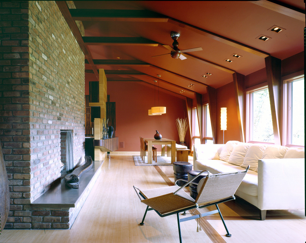 Exemple d'un salon tendance de taille moyenne et ouvert avec un mur orange, parquet clair, une cheminée standard et un manteau de cheminée en brique.