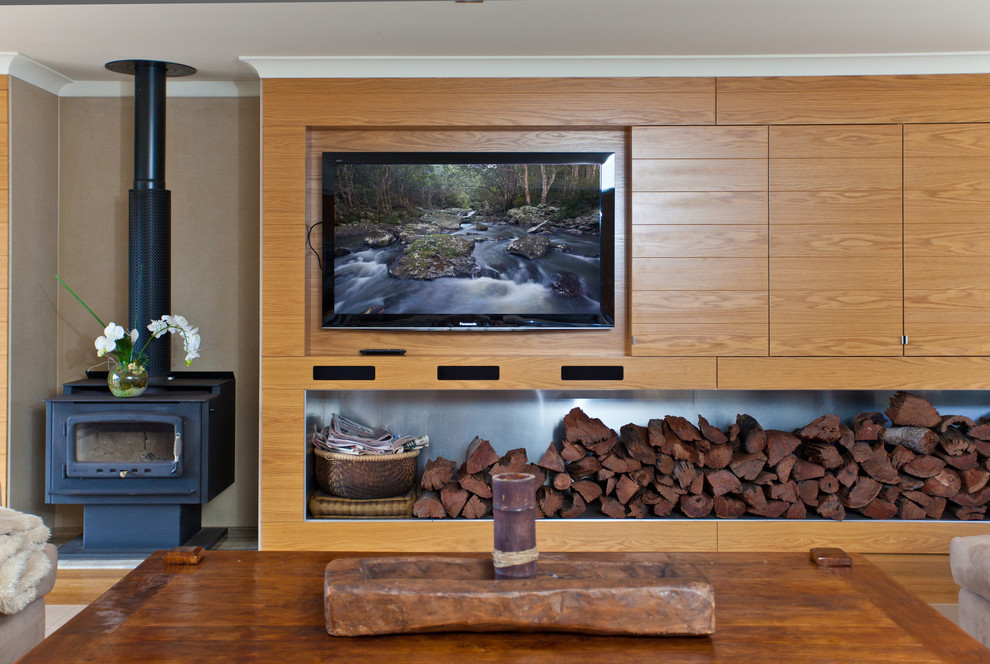 Ispirazione per un soggiorno tropicale con TV a parete e stufa a legna