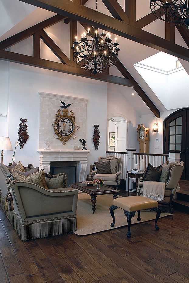 Пример оригинального дизайна: большая гостиная комната в классическом стиле с белыми стенами, темным паркетным полом, стандартным камином, фасадом камина из камня, коричневым полом и балками на потолке