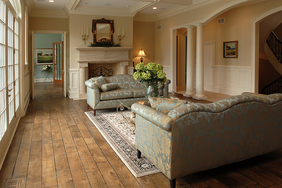 Cette photo montre un grand salon avec un sol en bois brun, une cheminée standard, un manteau de cheminée en pierre, un sol marron et un plafond à caissons.