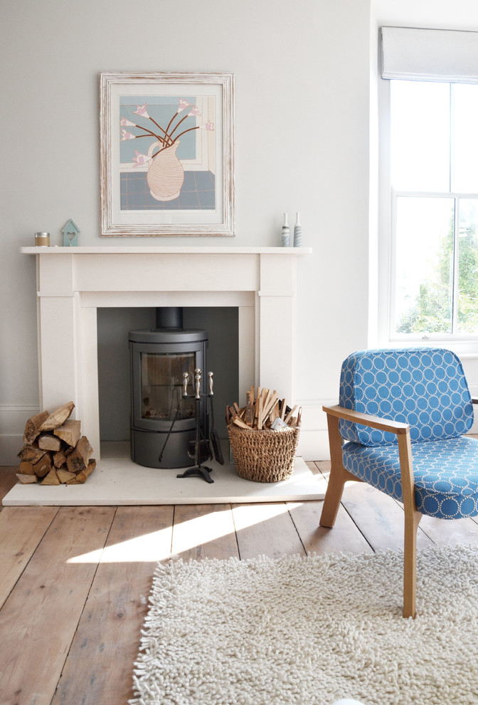 Example of a transitional light wood floor living room design in Cornwall with a wood stove and white walls