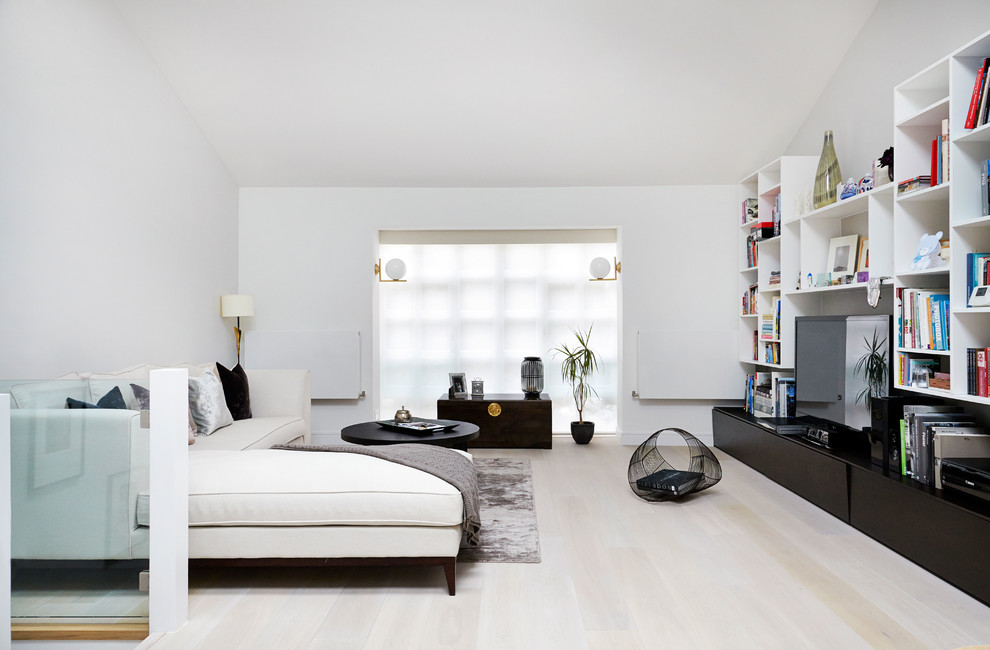 Стильный дизайн: открытая гостиная комната в современном стиле с светлым паркетным полом, отдельно стоящим телевизором и серыми стенами без камина - последний тренд