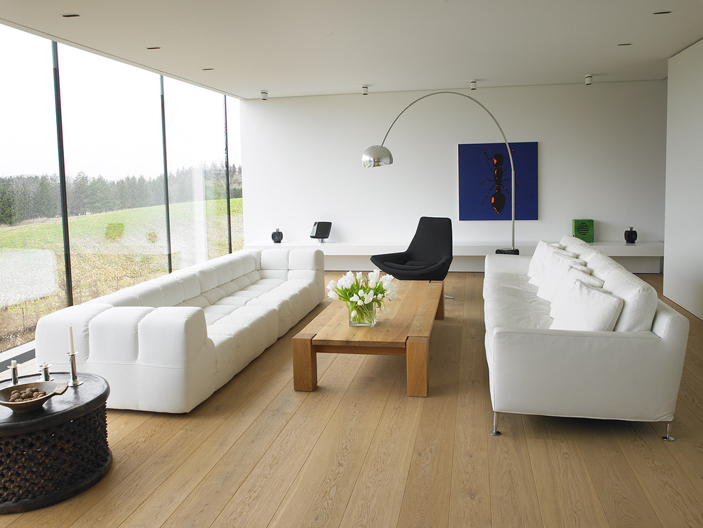 На фото: гостиная комната в стиле модернизм с белыми стенами и паркетным полом среднего тона с