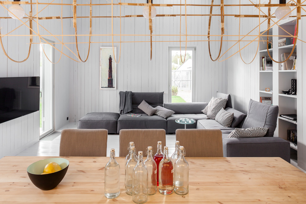 Modelo de salón para visitas abierto nórdico con paredes blancas, suelo de madera pintada y televisor colgado en la pared