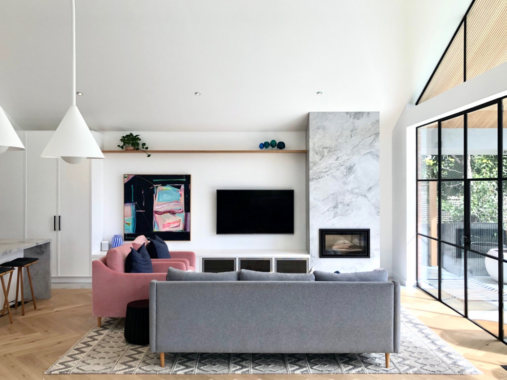 Inredning av ett modernt allrum med öppen planlösning, med vita väggar, ljust trägolv, en standard öppen spis, en väggmonterad TV och beiget golv