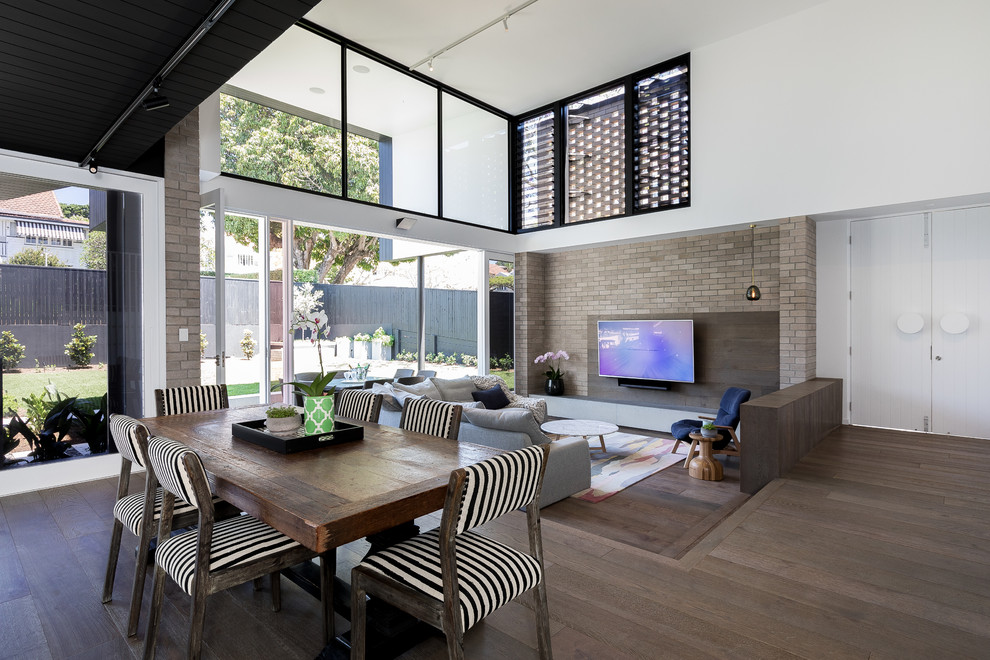 Modernes Wohnzimmer mit weißer Wandfarbe, braunem Holzboden, TV-Wand und braunem Boden in Brisbane