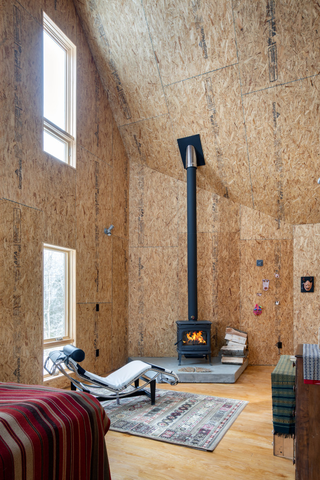 Modelo de salón abierto y abovedado actual de tamaño medio con estufa de leña, madera, madera, suelo de contrachapado y marco de chimenea de hormigón