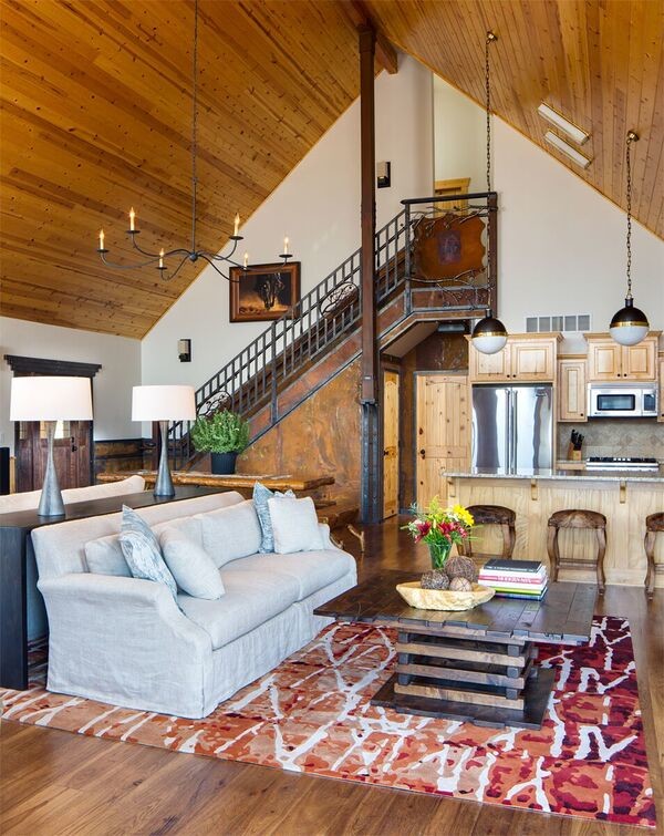 Modelo de salón tipo loft rural de tamaño medio con paredes blancas, suelo de madera clara, estufa de leña, marco de chimenea de metal y televisor colgado en la pared