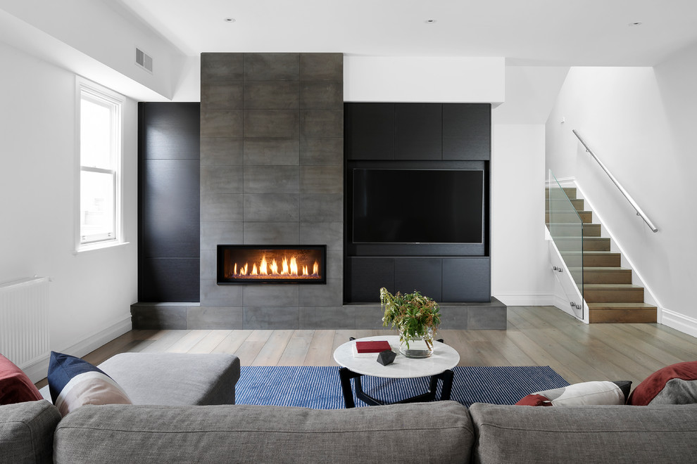 メルボルンにあるコンテンポラリースタイルのおしゃれなリビング (石材の暖炉まわり、埋込式メディアウォール、白い壁、無垢フローリング、横長型暖炉、ベージュの床) の写真