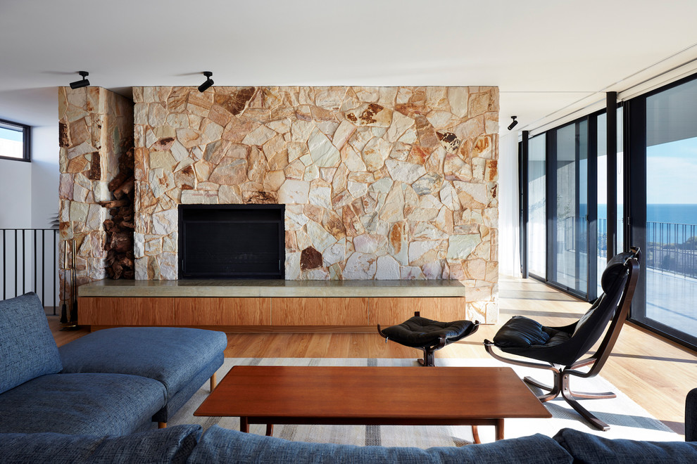 Idee per un soggiorno moderno con pareti bianche, pavimento in legno massello medio, camino classico, cornice del camino in pietra e pavimento marrone