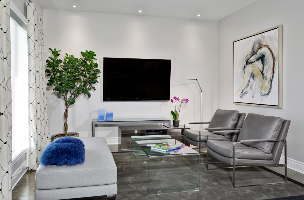 Imagen de salón abierto actual de tamaño medio con paredes grises, suelo de madera oscura y televisor colgado en la pared