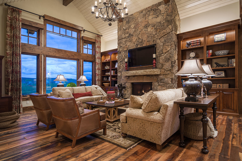 Large mountain style open concept dark wood floor living room library photo in Salt Lake City with white walls, a standard fireplace, a stone fireplace and a wall-mounted tv