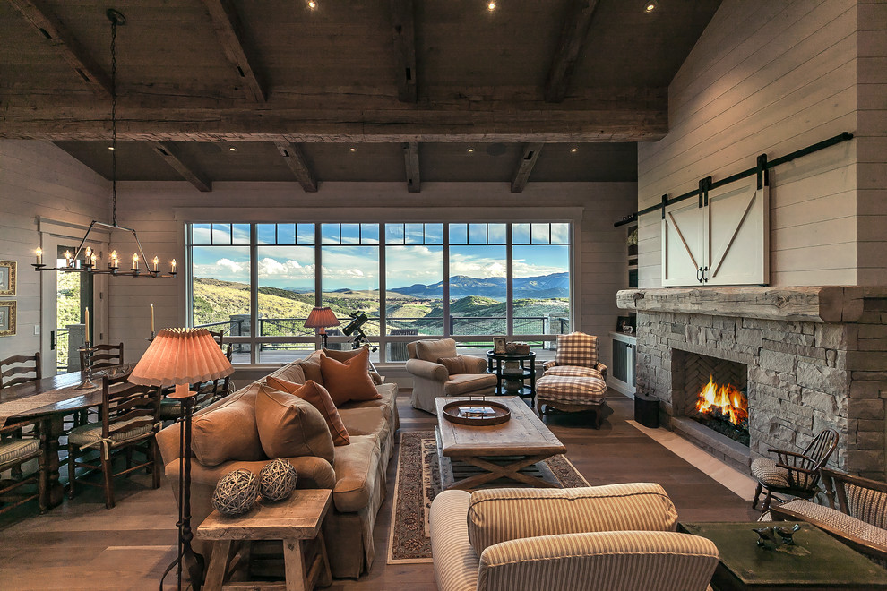 Example of a large transitional open concept medium tone wood floor, exposed beam and shiplap wall living room design in Salt Lake City with white walls, a standard fireplace, a stone fireplace and a concealed tv