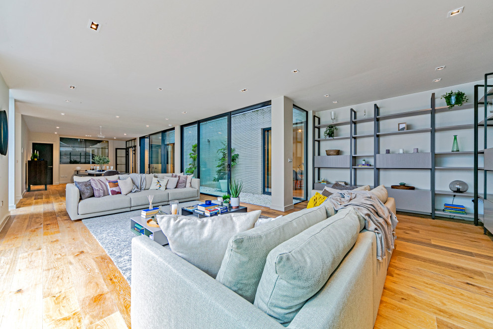 Idee per un soggiorno design aperto con pareti beige, pavimento in legno massello medio e pavimento marrone