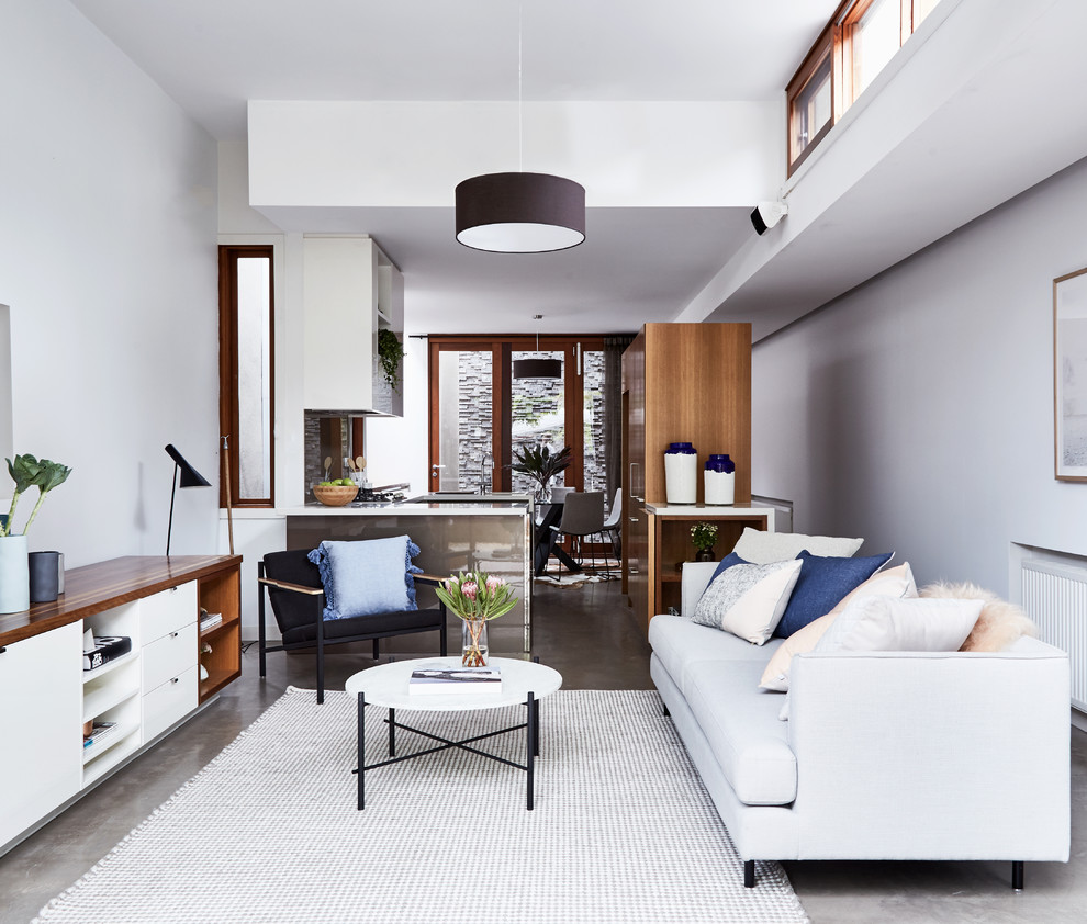 Cette photo montre un salon tendance ouvert avec un mur gris et sol en béton ciré.