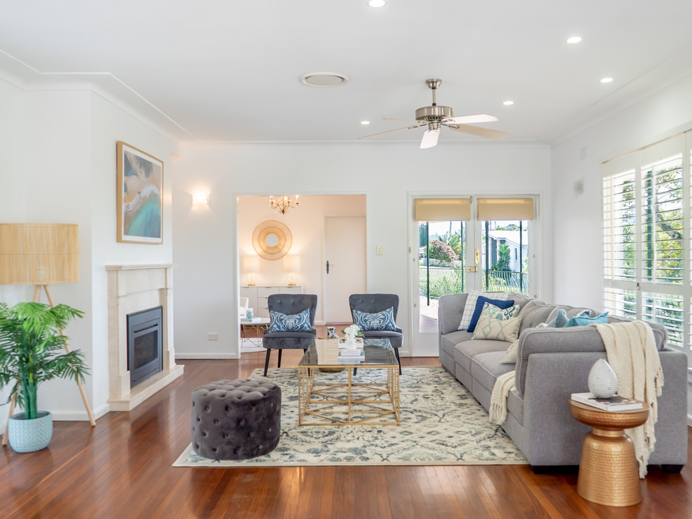 Example of a beach style formal medium tone wood floor and brown floor living room design in Other with white walls, a standard fireplace and no tv