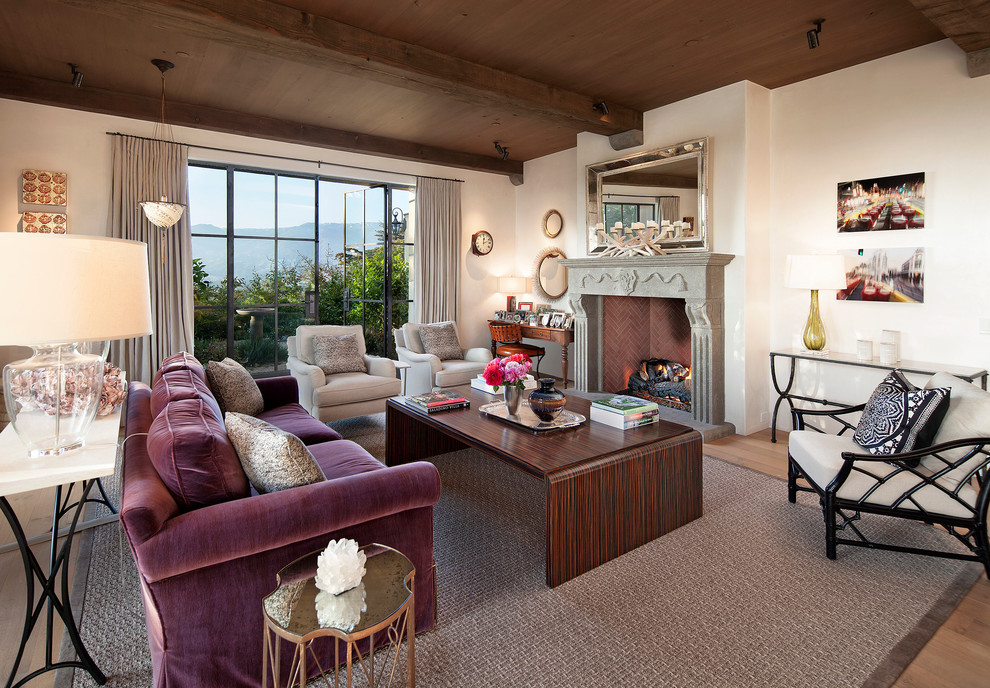 Example of a tuscan medium tone wood floor living room design in Santa Barbara with white walls and a standard fireplace