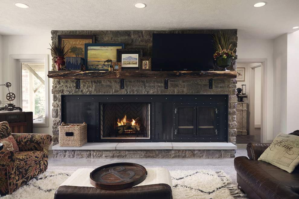 他の地域にある巨大なラスティックスタイルのおしゃれなLDK (白い壁、標準型暖炉、石材の暖炉まわり、据え置き型テレビ、グレーの床、コンクリートの床) の写真