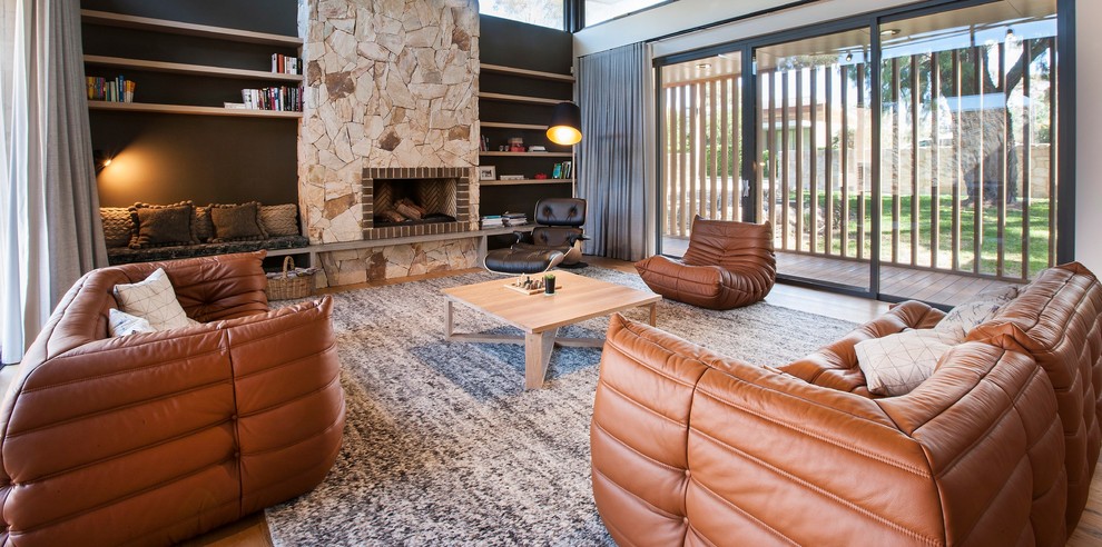 Mittelgroßes, Fernseherloses, Offenes Modernes Wohnzimmer mit schwarzer Wandfarbe, braunem Holzboden, Kamin und Kaminumrandung aus Stein in Adelaide