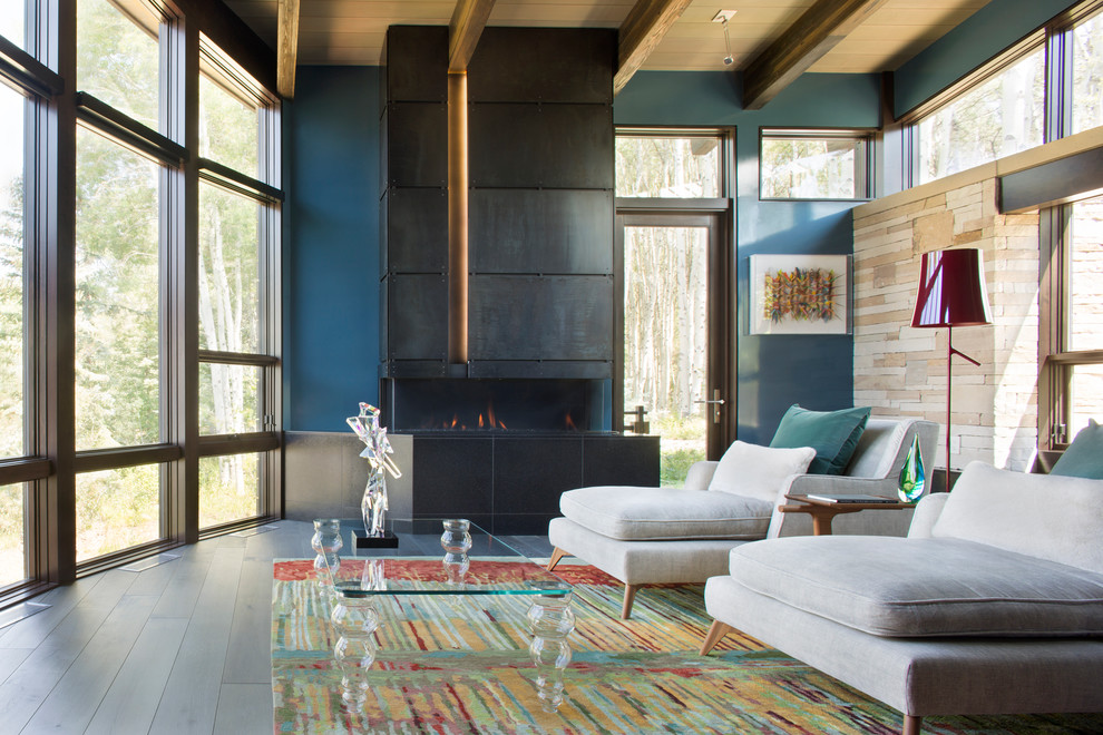 Cette image montre un salon design avec un mur bleu, une cheminée ribbon, un manteau de cheminée en métal, une salle de réception, parquet foncé et aucun téléviseur.