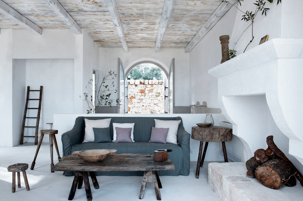 Immagine di un soggiorno country aperto con pareti bianche, camino classico e cornice del camino in intonaco