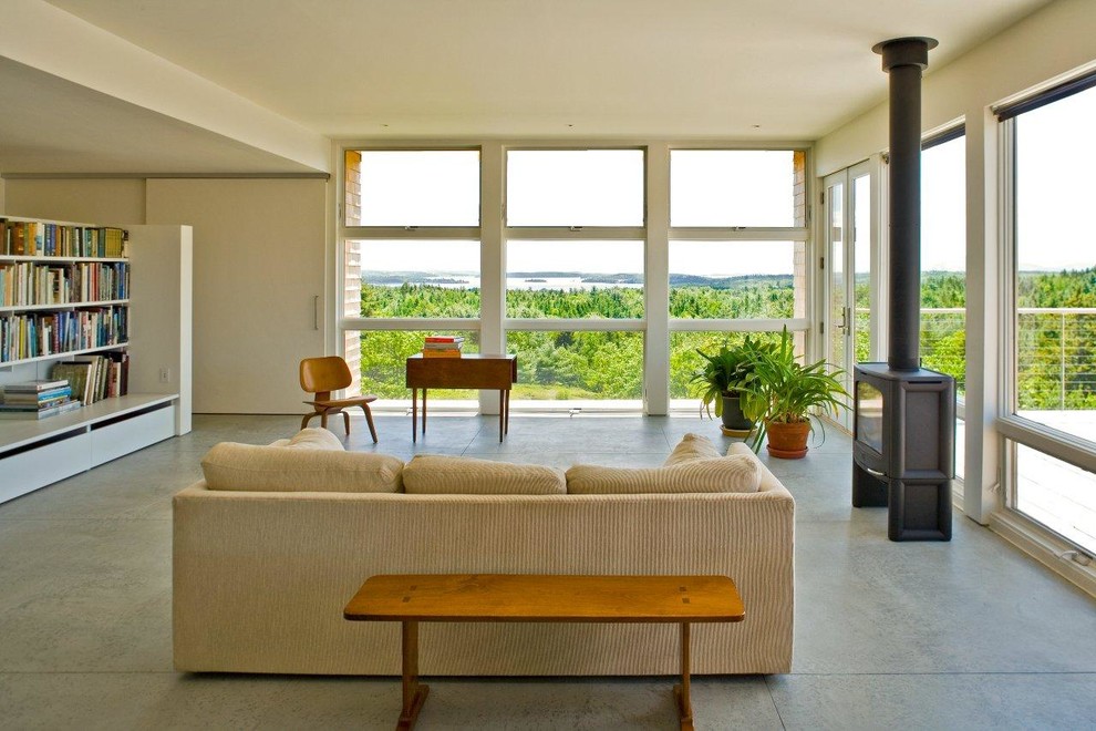Immagine di un soggiorno minimalista con pavimento in cemento, pareti bianche e stufa a legna