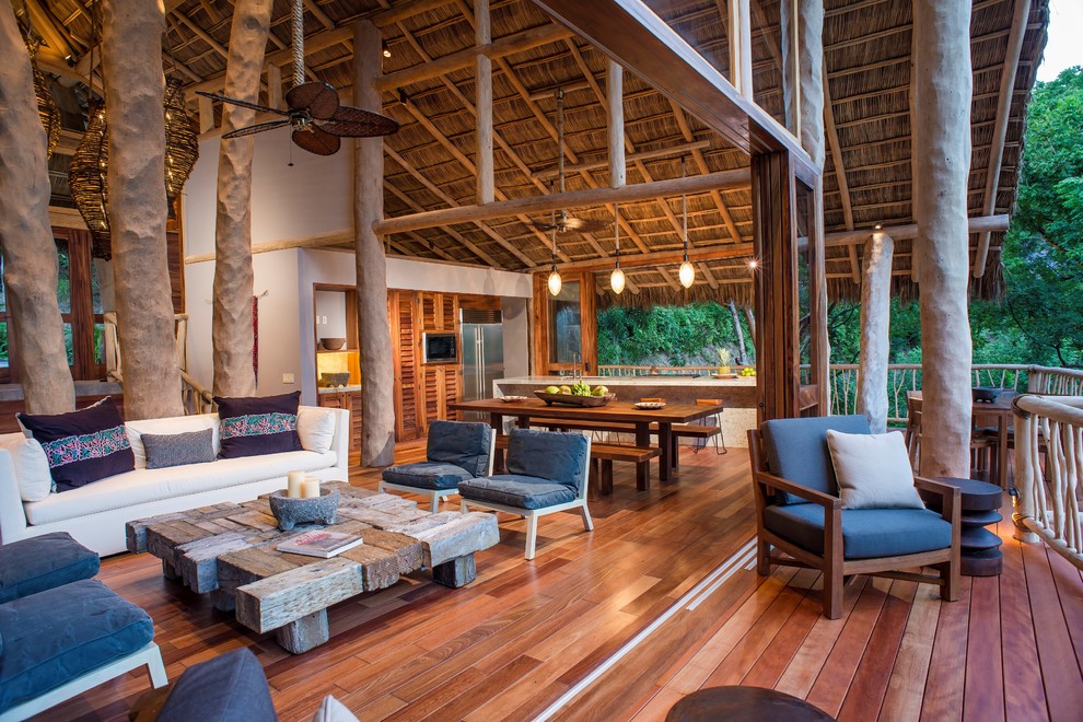 Ejemplo de salón abierto tropical extra grande con paredes blancas y suelo de madera en tonos medios