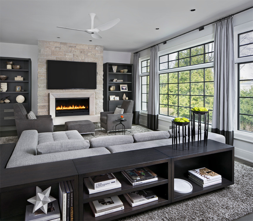 This is an example of a large contemporary open plan living room in Detroit with grey walls, medium hardwood flooring, a standard fireplace, a stone fireplace surround and a wall mounted tv.