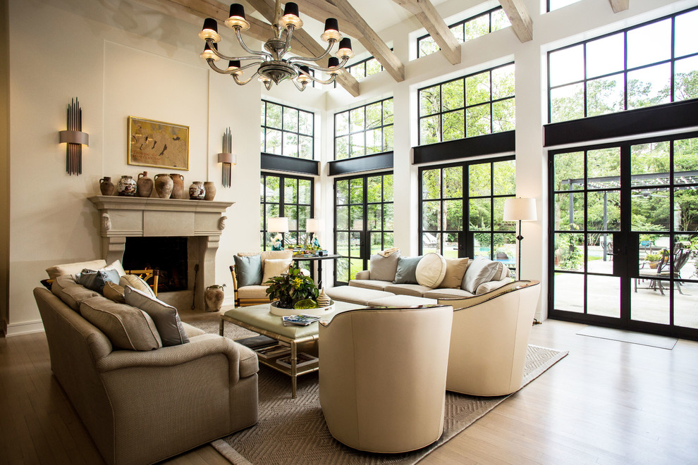 Repräsentatives Country Wohnzimmer mit weißer Wandfarbe, hellem Holzboden, Kamin, Kaminumrandung aus Stein und braunem Boden in Houston