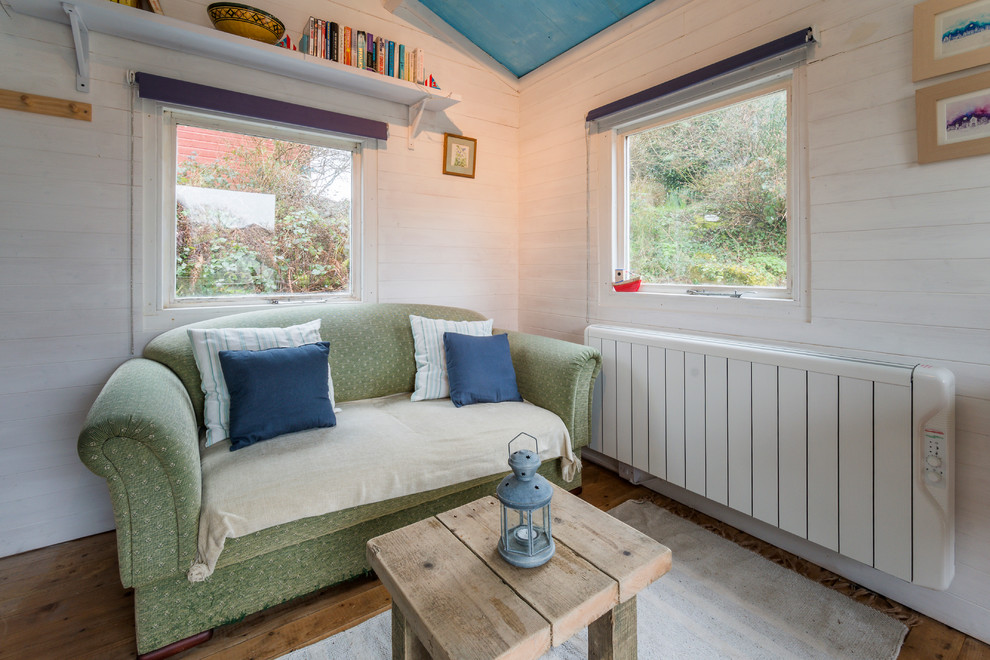 Idées déco pour un petit salon campagne ouvert avec un mur blanc et un sol en bois brun.