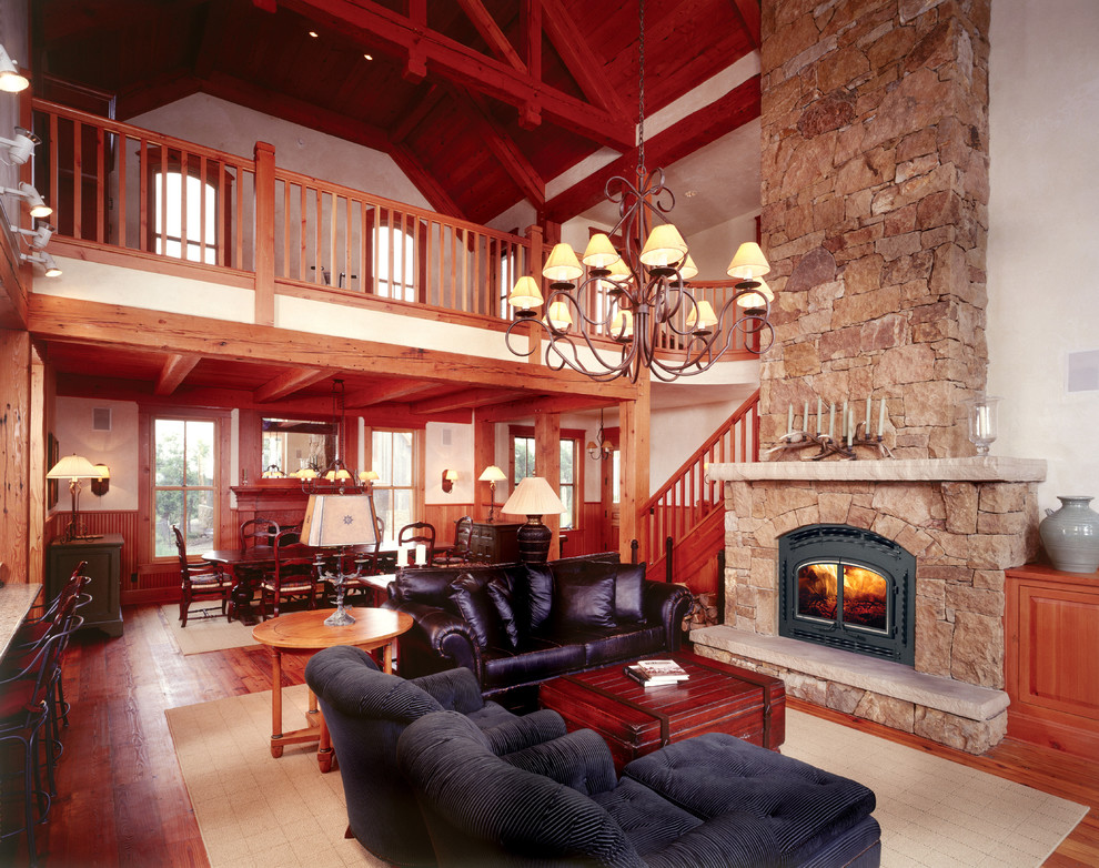 Imagen de salón abierto clásico grande con paredes beige, suelo de madera en tonos medios, estufa de leña, marco de chimenea de piedra y suelo marrón