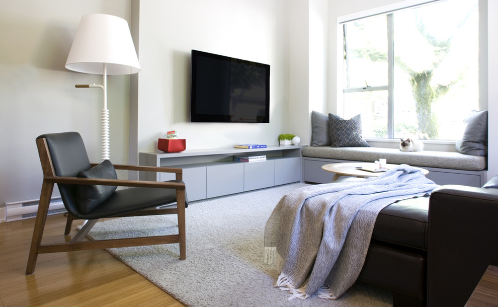 На фото: гостиная комната в современном стиле с белыми стенами и телевизором на стене