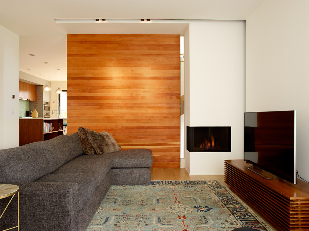 Inspiration for a small modern open concept light wood floor living room remodel in Seattle with white walls, a two-sided fireplace, a plaster fireplace and a tv stand