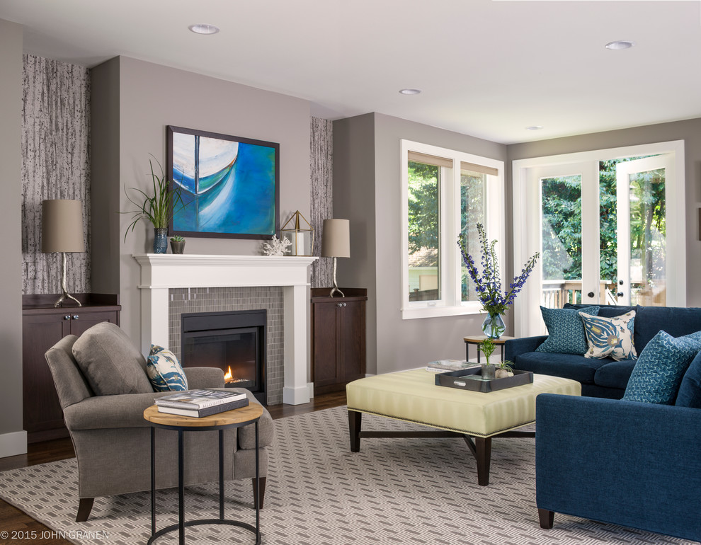 Стильный дизайн: большая открытая гостиная комната в стиле неоклассика (современная классика) с серыми стенами, стандартным камином, фасадом камина из плитки и синим диваном без телевизора - последний тренд