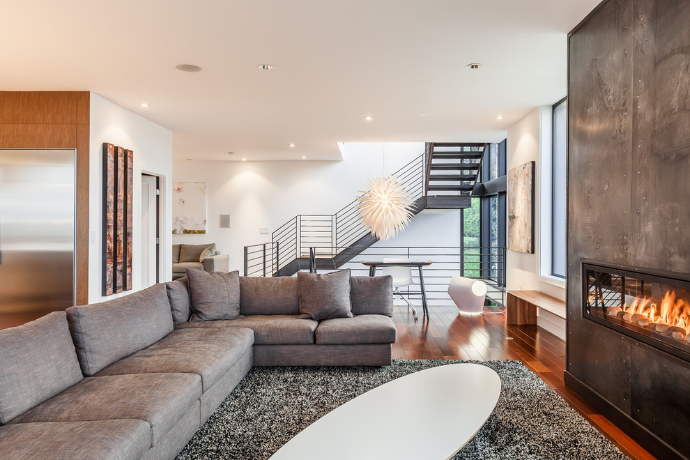Offenes Modernes Wohnzimmer mit weißer Wandfarbe, dunklem Holzboden, Gaskamin und Kaminumrandung aus Metall in Seattle
