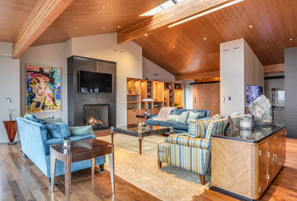 Immagine di un grande soggiorno moderno con pareti beige, pavimento in legno massello medio, camino classico e TV a parete