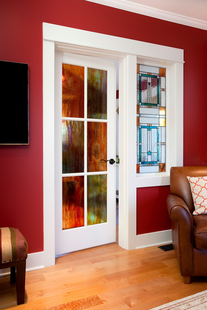 На фото: гостиная комната среднего размера в стиле кантри с красными стенами, паркетным полом среднего тона, телевизором на стене, стандартным камином и фасадом камина из плитки с