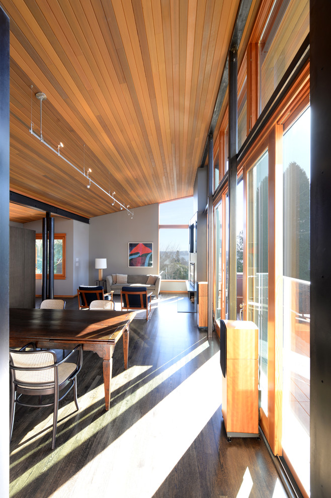 Mittelgroßes, Fernseherloses, Offenes Modernes Wohnzimmer mit grauer Wandfarbe, dunklem Holzboden, Kaminofen und Kaminumrandung aus Metall in Seattle