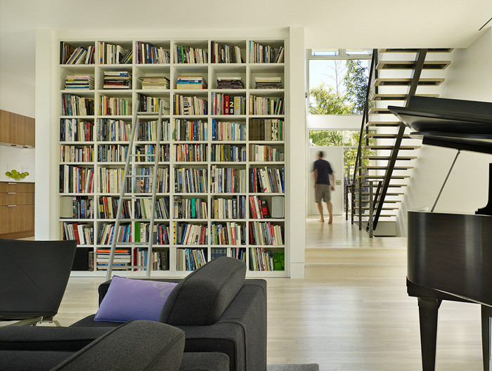 Esempio di un soggiorno chic di medie dimensioni e aperto con libreria, pareti bianche e parquet chiaro