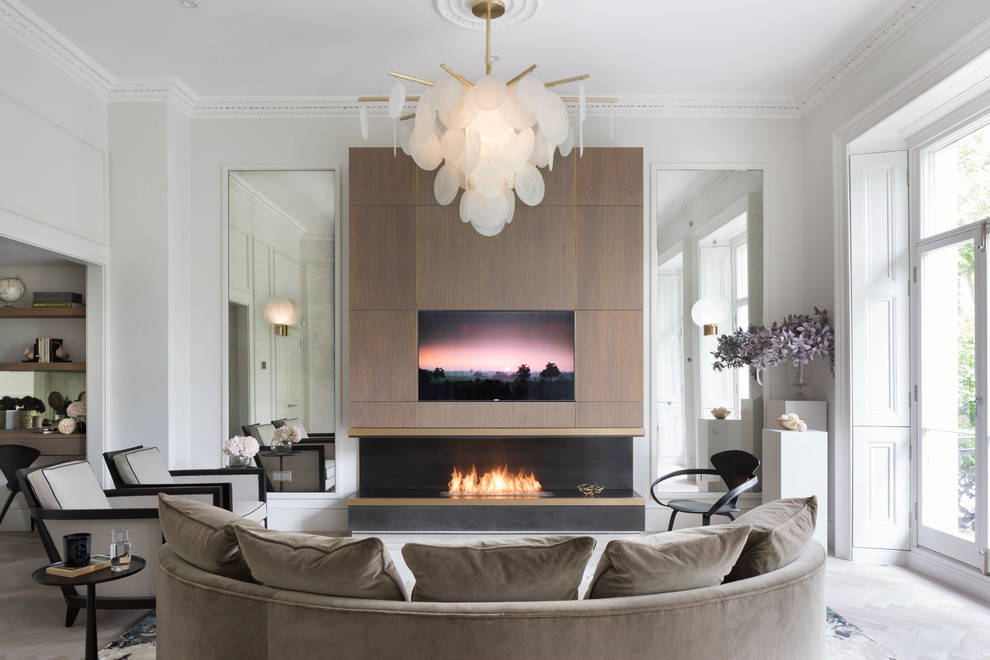 Стильный дизайн: гостиная комната в современном стиле с белыми стенами, стандартным камином и скрытым телевизором - последний тренд
