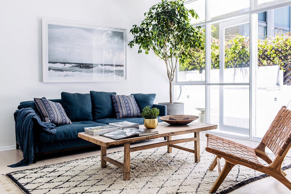 Свежая идея для дизайна: гостиная комната в скандинавском стиле с белыми стенами, светлым паркетным полом, бежевым полом и синим диваном - отличное фото интерьера
